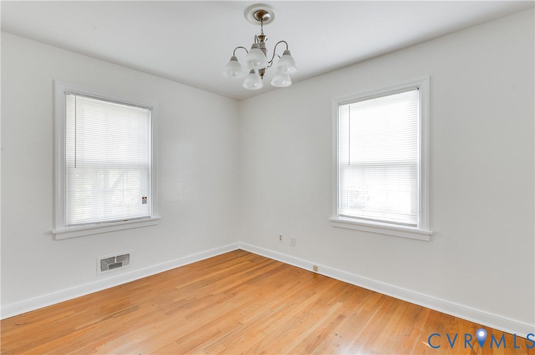 1701 Kingswood Street, Richmond, VA 23224 Room featuring wood-finish flooring, two windows with blinds, and a multi-arm chandelier with glass shades