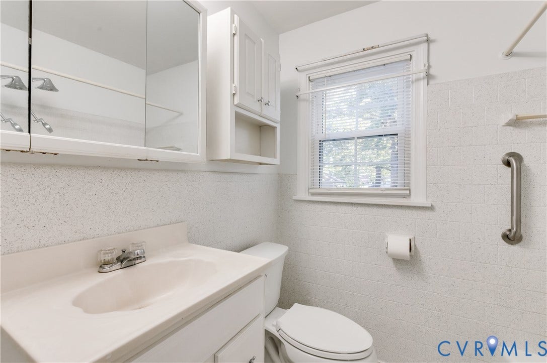 1701 Kingswood Street, Richmond, VA 23224 Bathroom featuring a vanity with integrated sink, mirrored medicine cabinet, wall-mounted storage cabinetry, window with blinds, and tiled wall surround