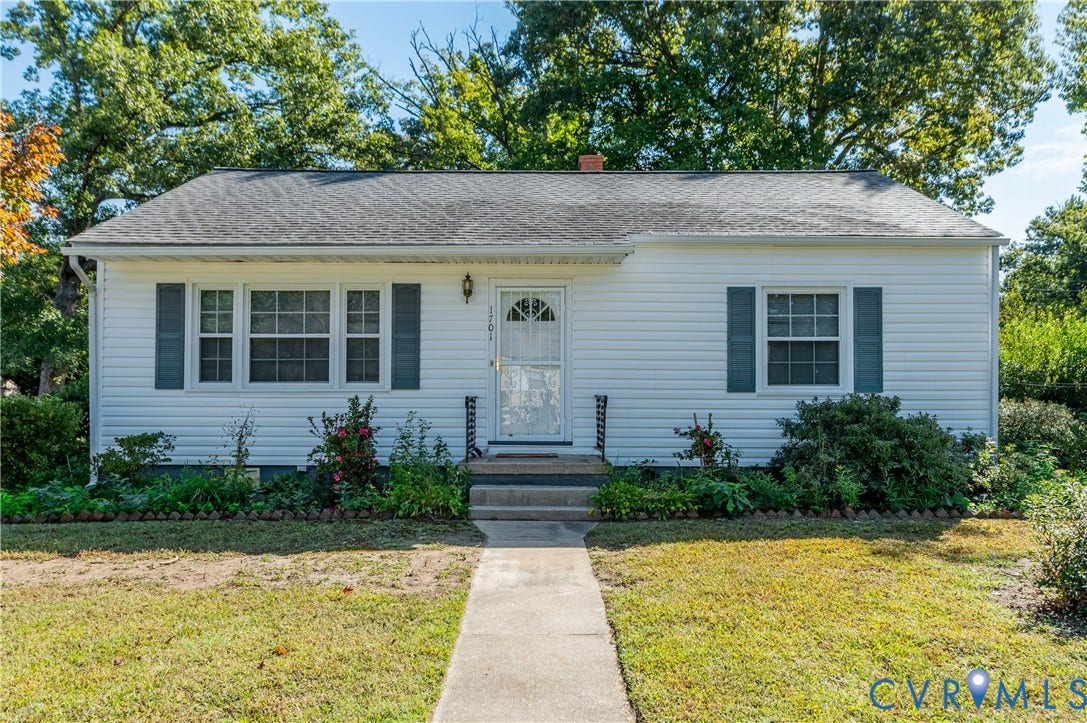 1701 Kingswood Street, Richmond, VA 23224 Exterior featuring white siding, dark window shutters, a front door with decorative glass inlay, and concrete walkway