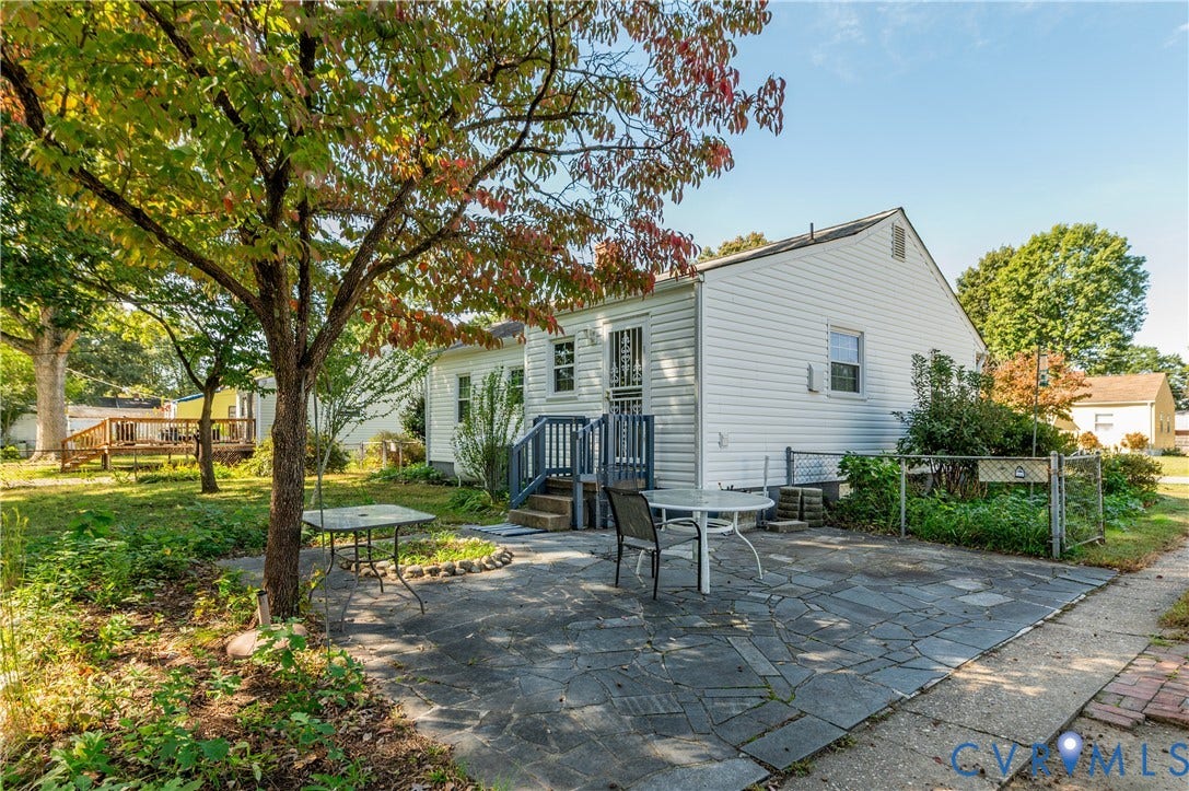 1701 Kingswood Street, Richmond, VA 23224 Exterior rear elevation featuring white siding, a flagstone patio, metal railing, and mature landscaping