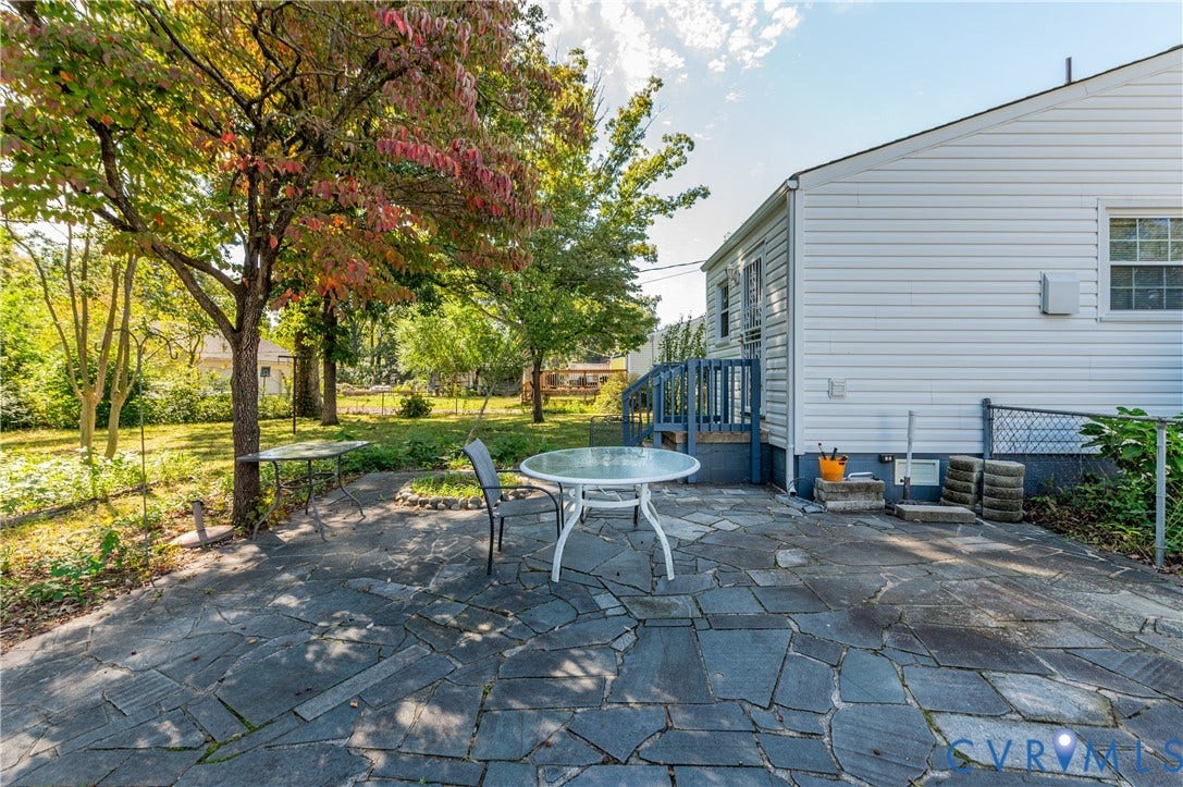 1701 Kingswood Street, Richmond, VA 23224 Flagstone patio, horizontal vinyl siding, elevated wooden exterior staircase, and mature trees on the lot