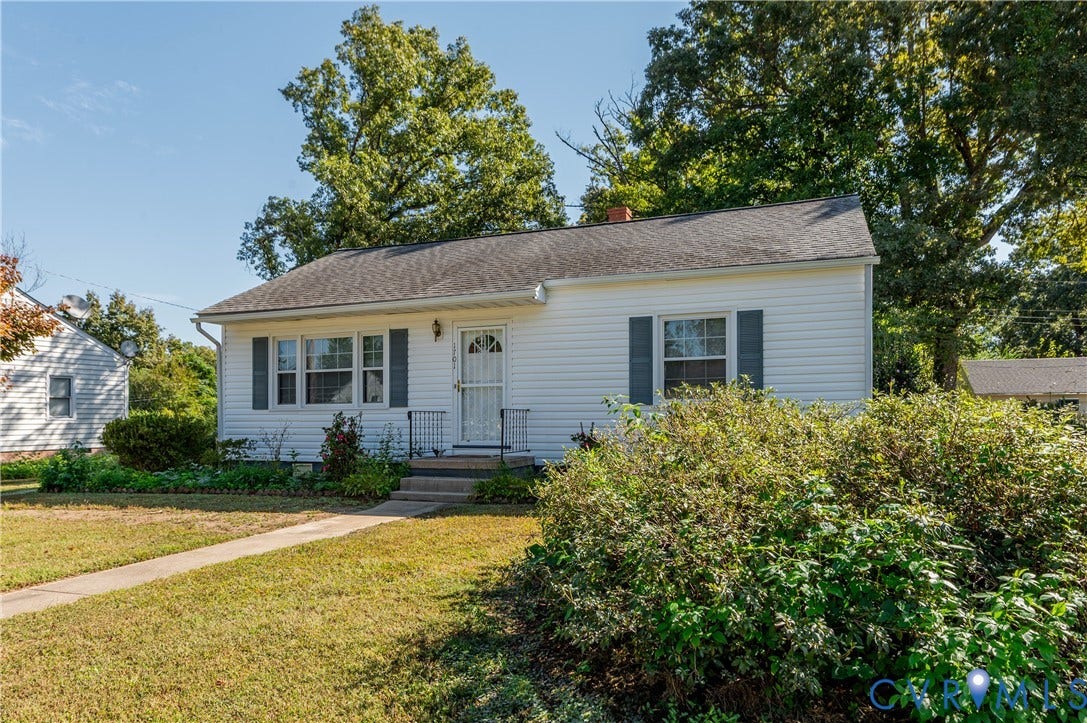 1701 Kingswood Street, Richmond, VA 23224 Single-story residence featuring white horizontal siding, dark shutters, a front storm door, a shingled roof, and a concrete walkway
