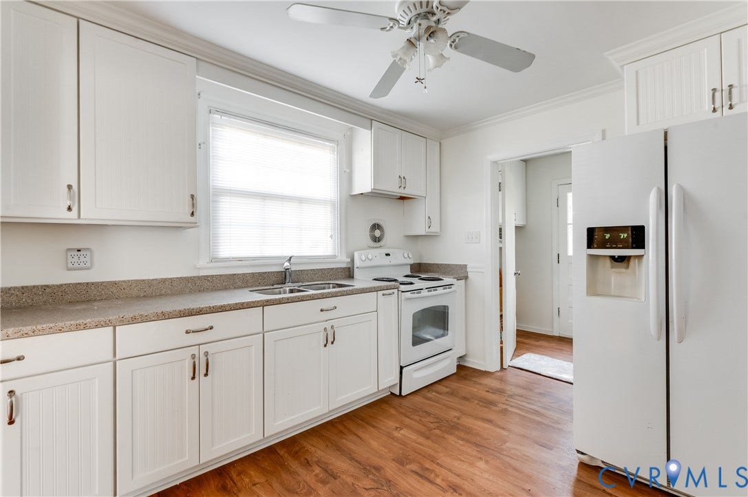 1701 Kingswood Street, Richmond, VA 23224 Kitchen featuring white shaker-style cabinetry, solid-surface countertops, dual-basin stainless steel sink, wood-finish flooring, and ceiling-mounted fan