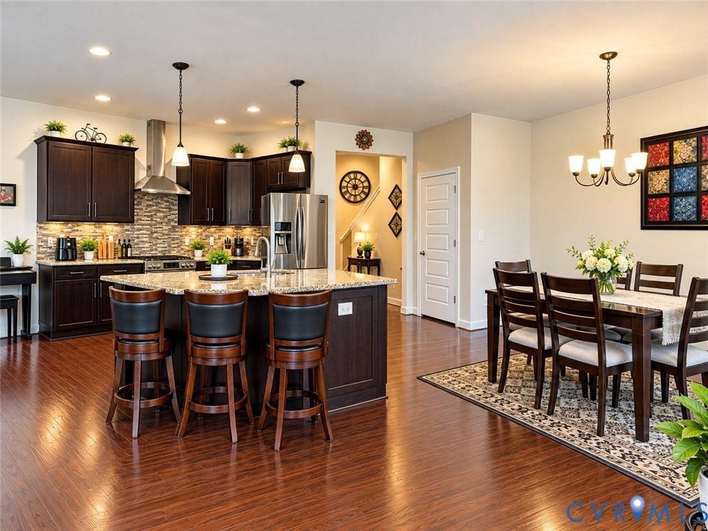 10507 Benoni Trail, Glen Allen, VA 23059 Open-concept living area featuring rich wood-finish flooring, a kitchen with dark cabinetry and stainless steel appliances, a center island with bar seating, and a dining area with an overhead chandelier