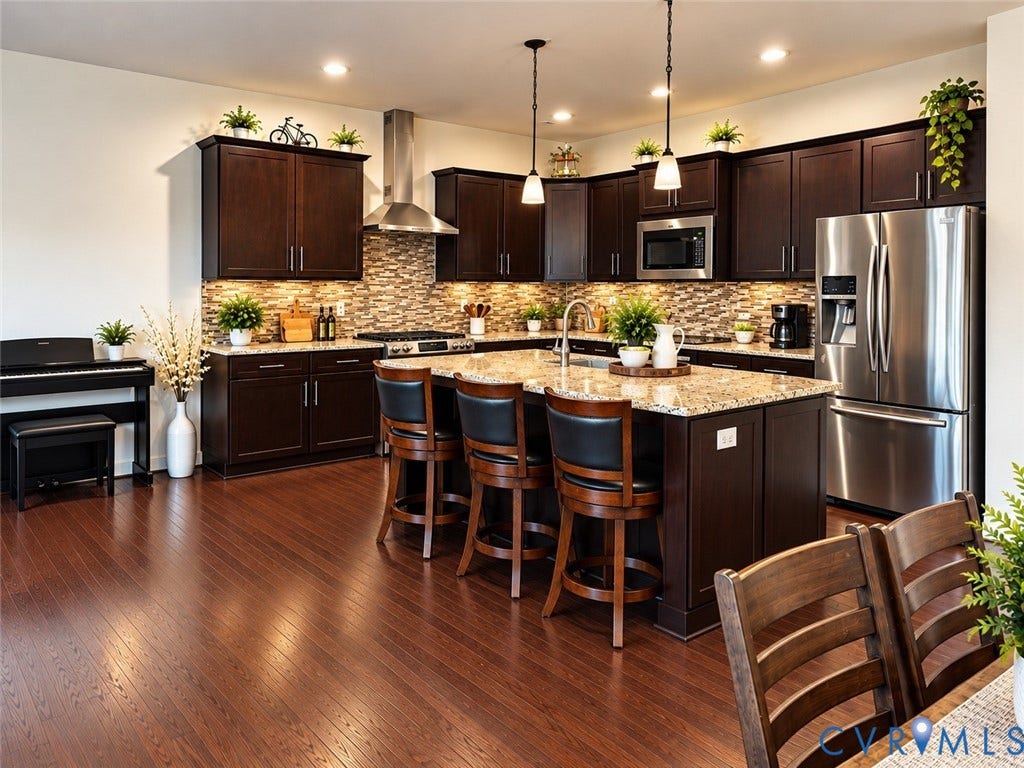 10507 Benoni Trail, Glen Allen, VA 23059 Expansive kitchen featuring dark wood cabinetry, stainless steel appliances, a multi-tone tile backsplash, and a large center island with a light-toned countertop