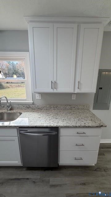 Kitchen featuring white shaker-style cabinetry, light-toned countertop, stainless steel dishwasher, and wood-finish flooring