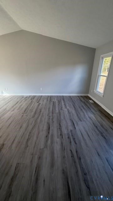 Vaulted ceiling enhancing vertical space, wood-finish flooring, and white trim throughout