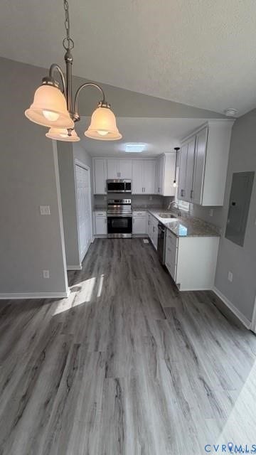 Kitchen featuring white cabinetry, stainless steel appliances, granite-style countertops, wood-finish flooring, and a skylight