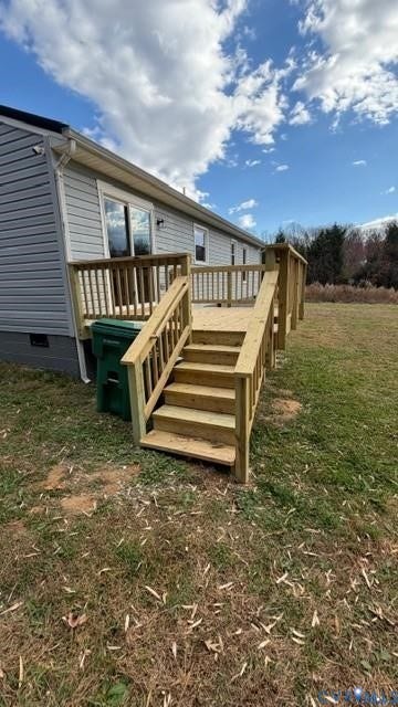 Expansive wood deck with stairs and an accessible ramp, featuring a light gray siding exterior and multiple sliding glass doors