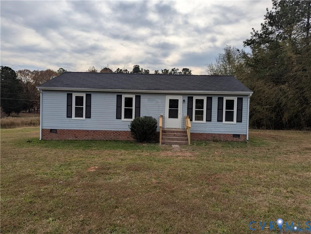 Light blue siding exterior with dark shutters, brick foundation, and a dark shingle roof