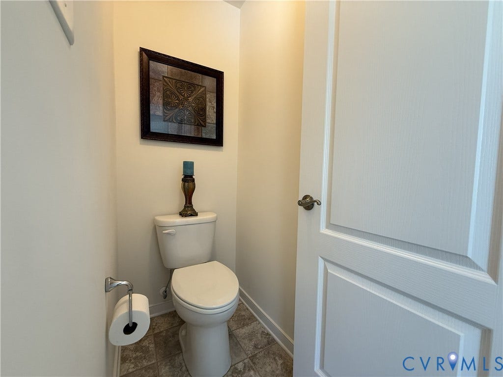 Two-panel interior door with a satin nickel lever handle, white porcelain toilet, and neutral tile flooring