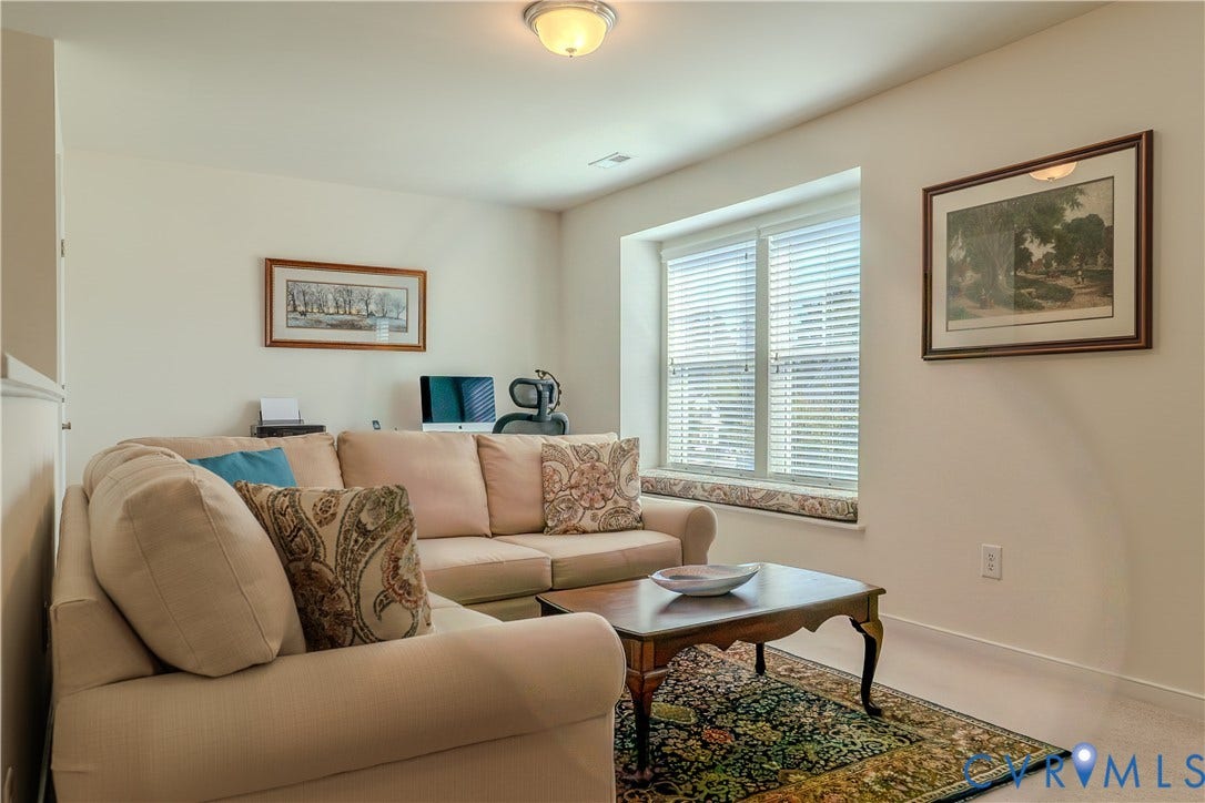 Interior space featuring neutral wall tones, a recessed window seat, horizontal blinds, and a central flush-mount ceiling light fixture