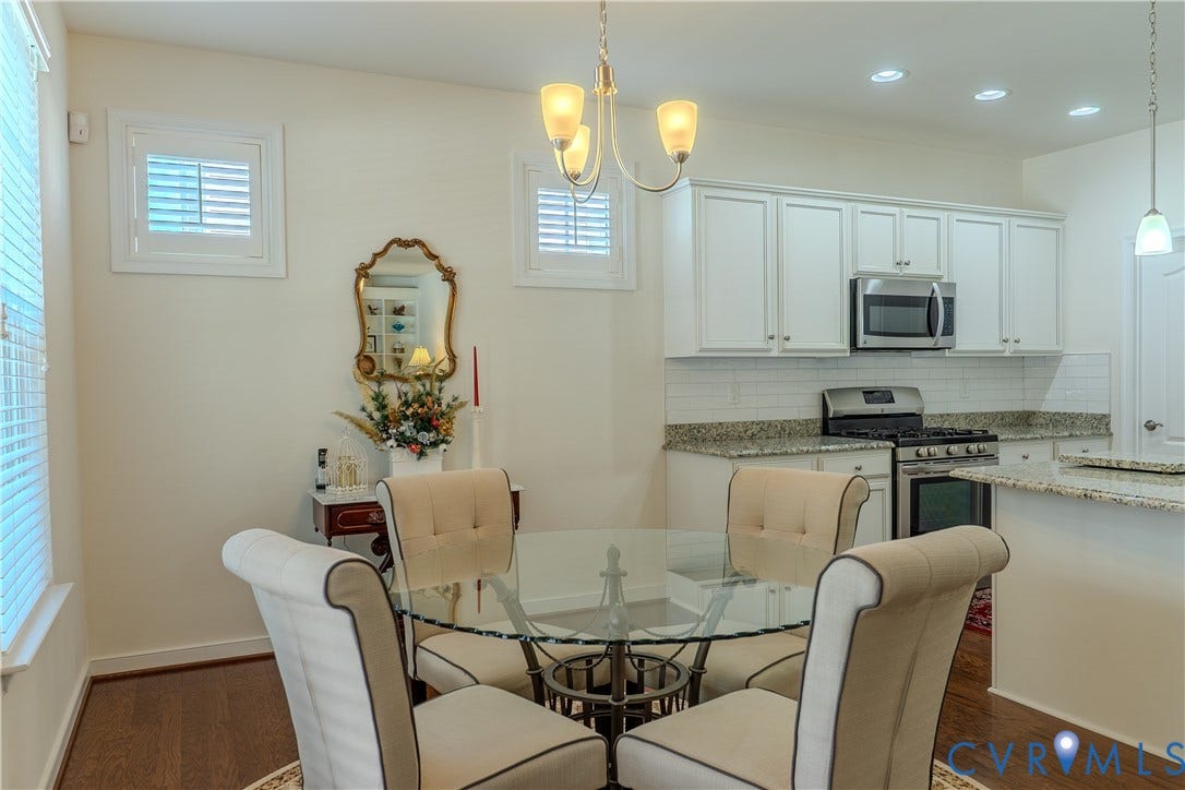Kitchen and dining area featuring white shaker-style cabinetry, stone countertops, a white subway tile backsplash, recessed lighting, and wood-finish flooring