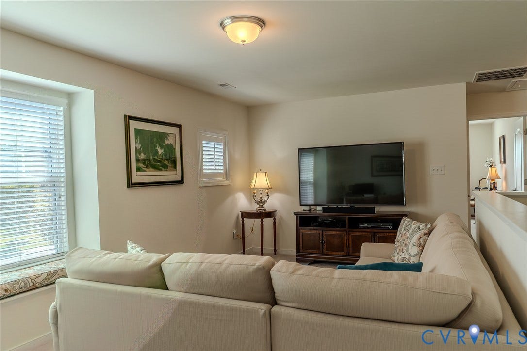 Living area featuring a recessed window seat, multi-pane window with white horizontal blinds, and a semi-flush mount ceiling light fixture