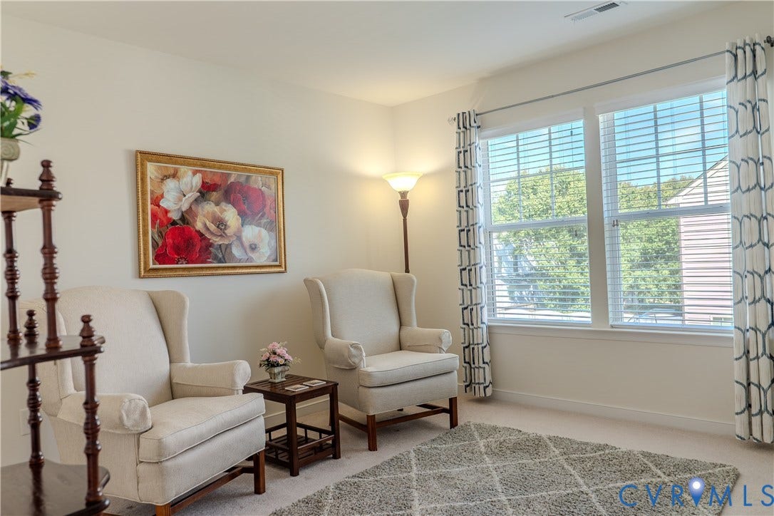 Neutral-toned interior space featuring expansive double-pane windows with horizontal blinds and carpeting
