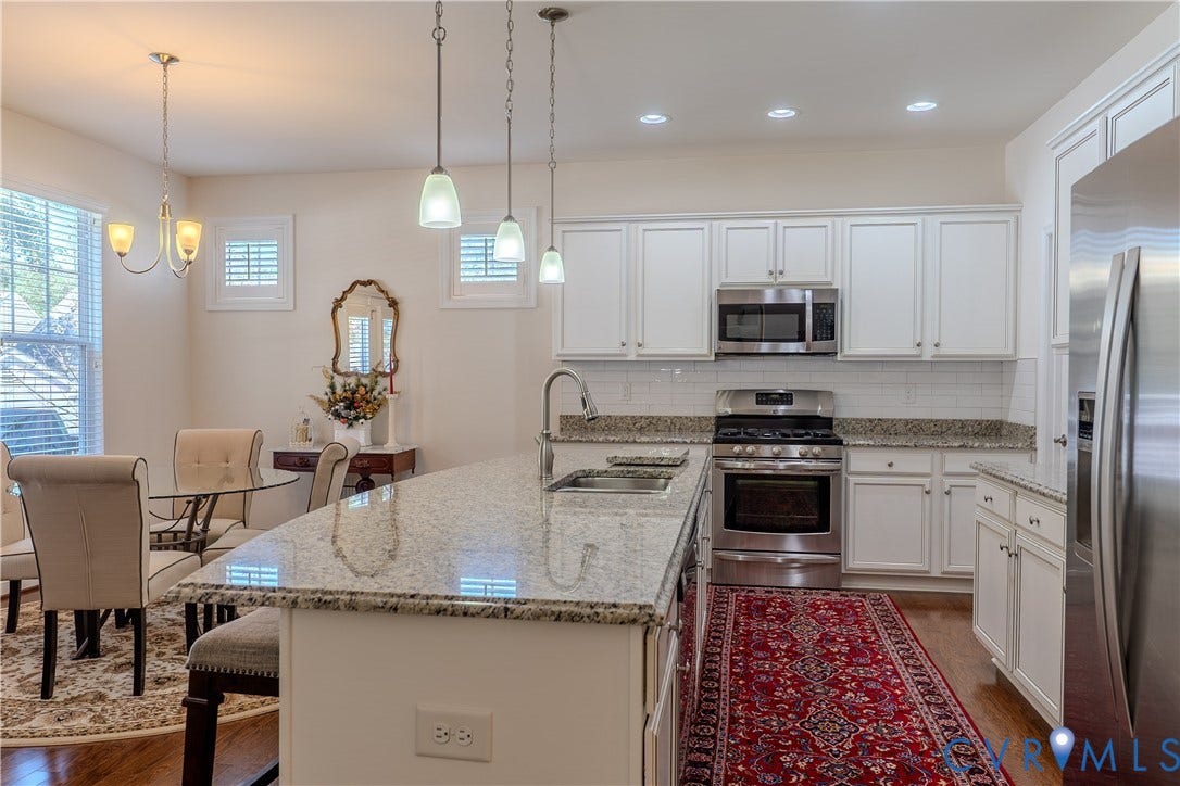 Kitchen featuring white cabinetry, stone-finish countertops, stainless steel appliances, a central island with an undermount sink, and recessed lighting