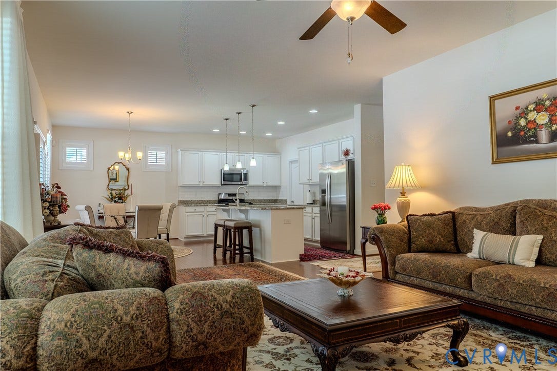 Kitchen featuring white shaker-style cabinetry, stone countertops, stainless steel appliances, a center island with pendant lighting, and wood-finish flooring