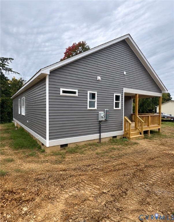 Grey horizontal siding exterior featuring a gable roof, white trim, and a natural wood-finish covered deck