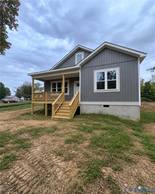 Exterior featuring vertical board-and-batten siding, a gabled roofline, and a covered wood porch with stairs