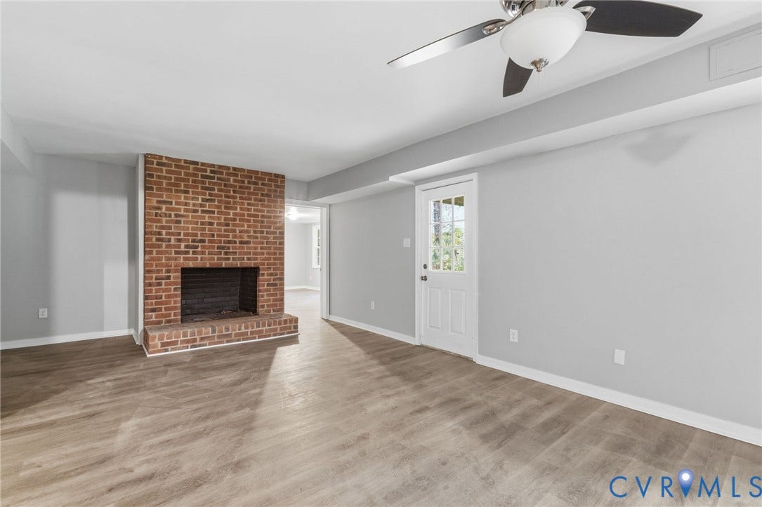 10731 Spring Run Road, Manchester, Chesterfield, VA 23832 Brick fireplace with hearth, wood-finish flooring, white paneled door with glass inserts, and a ceiling fan with integrated lighting