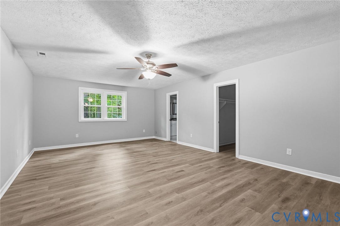 10731 Spring Run Road, Manchester, Chesterfield, VA 23832 Spacious room featuring wood-finish flooring, a ceiling fan, a window with white trim, and a doorway to a closet
