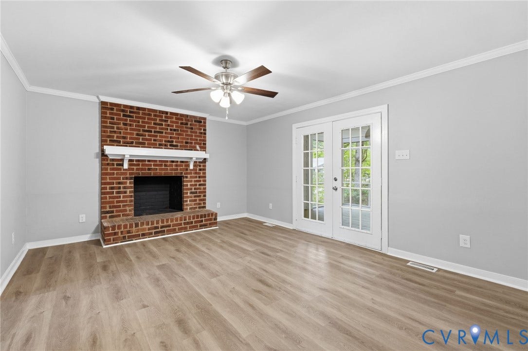 10731 Spring Run Road, Manchester, Chesterfield, VA 23832 Brick fireplace with a white mantel, wood-finish flooring, white double French doors, and ceiling fan with integrated lighting