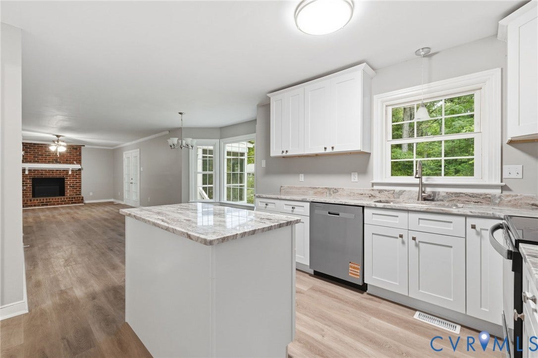 10731 Spring Run Road, Manchester, Chesterfield, VA 23832 White cabinetry with stainless steel appliances, a kitchen island with stone-finish countertops, wood-finish flooring, and a brick fireplace