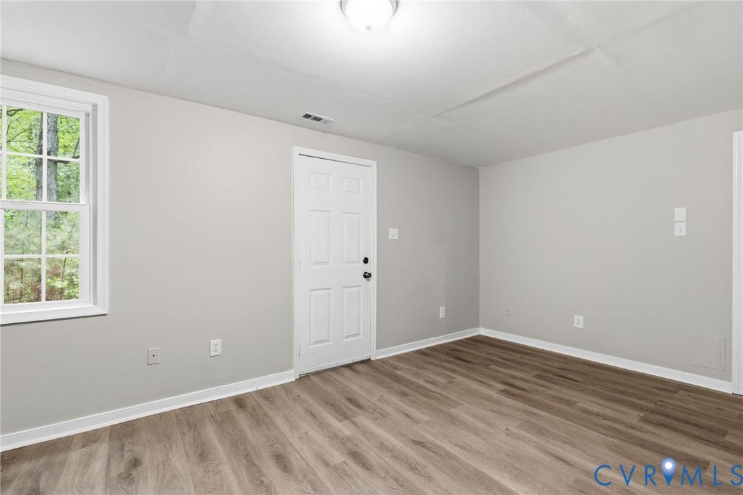 10731 Spring Run Road, Manchester, Chesterfield, VA 23832 Wood-finish flooring with light gray wall paint, a white paneled door, and a white window frame
