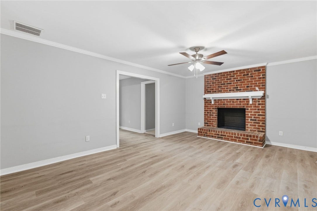 10731 Spring Run Road, Manchester, Chesterfield, VA 23832 Spacious room featuring wood-finish flooring, a brick fireplace with a white mantel, and a ceiling fan