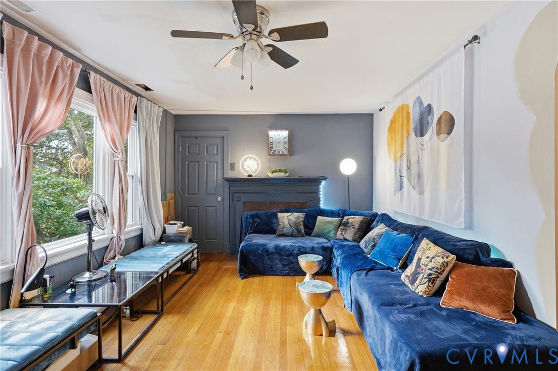 Hardwood flooring, painted fireplace mantel, ceiling fan, and prominent windows