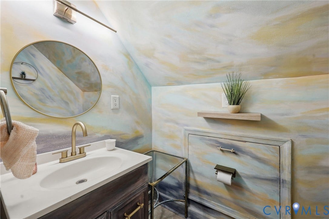 Vanity with integrated sink, brass-finish faucet, and coordinating oval mirror