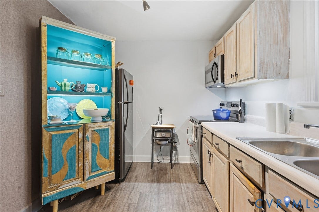Wood-finish flooring, stainless steel appliances, upper and lower cabinetry, white countertops, and a double basin sink