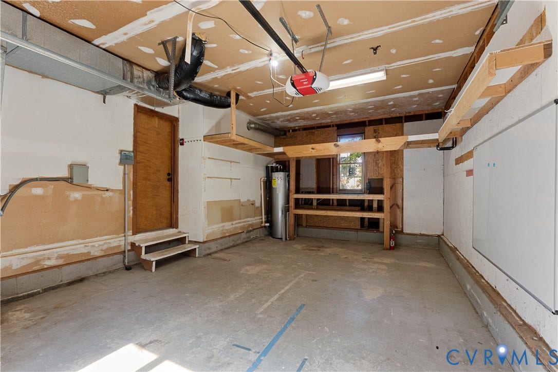 2307 Garrison Place Terrace, Garrison Place, Midlothian, VA 23112 Garage featuring concrete flooring, built-in wooden shelving, a water heater, and a dedicated utility door