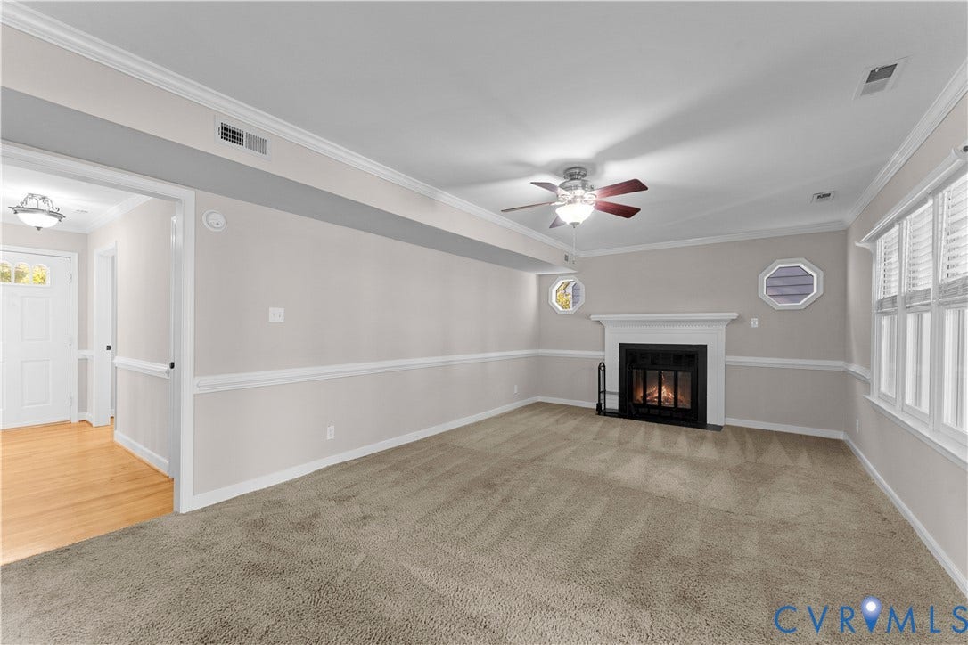 2307 Garrison Place Terrace, Garrison Place, Midlothian, VA 23112 Living room featuring a fireplace with a white mantel, neutral carpeting, decorative chair rail molding, crown molding, and two octagonal accent windows