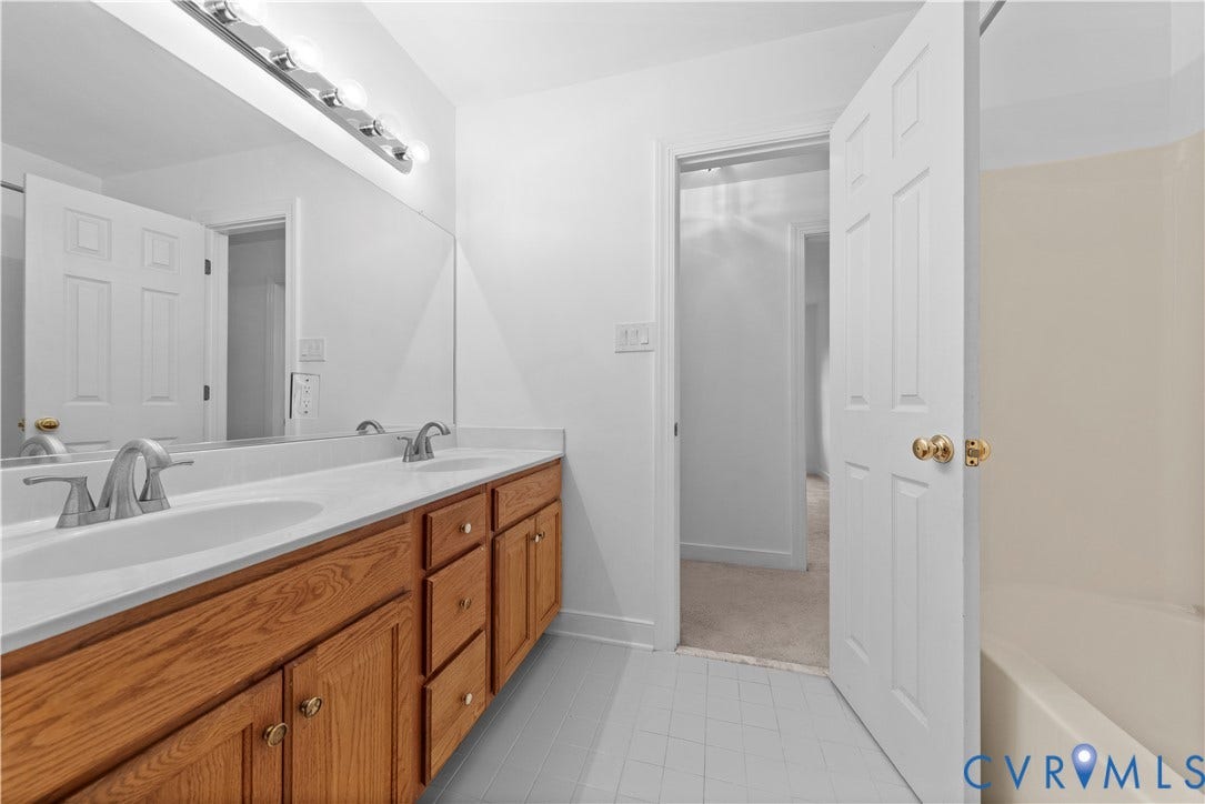 3437 Riverton Court, Robious Road Corridor, Midlothian, VA 23113 Double vanity featuring wood-finish cabinetry, solid surface countertop with integrated dual sinks, chrome fixtures, and a full-width mirror