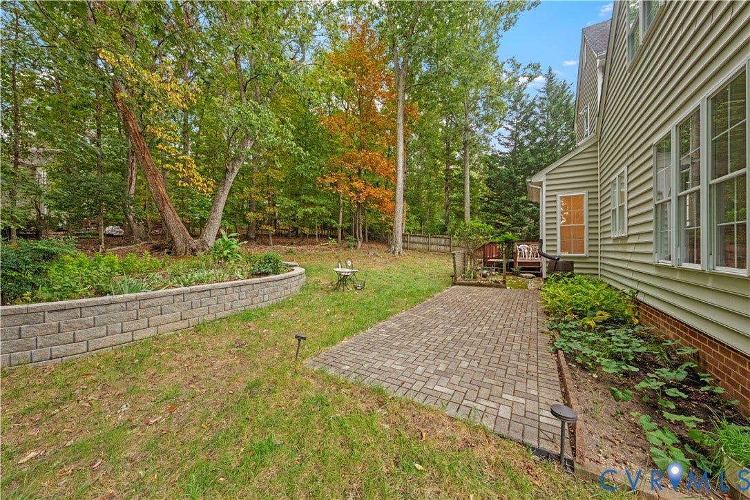 3437 Riverton Court, Robious Road Corridor, Midlothian, VA 23113 Backyard featuring a paver patio, stone-block retaining wall, landscape beds, and mature perimeter trees