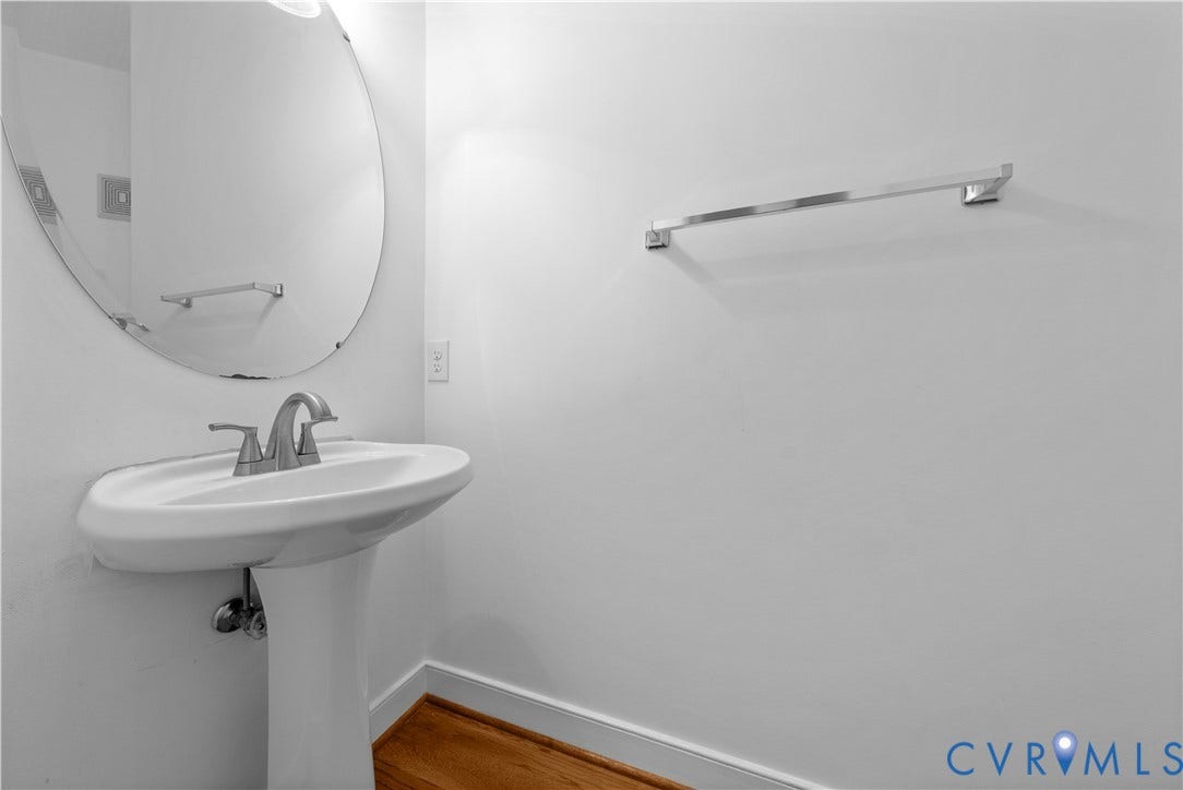 3437 Riverton Court, Robious Road Corridor, Midlothian, VA 23113 Pedestal sink featuring a polished chrome faucet, oval wall-mounted mirror, and wall-mounted towel bar over wood-finish flooring