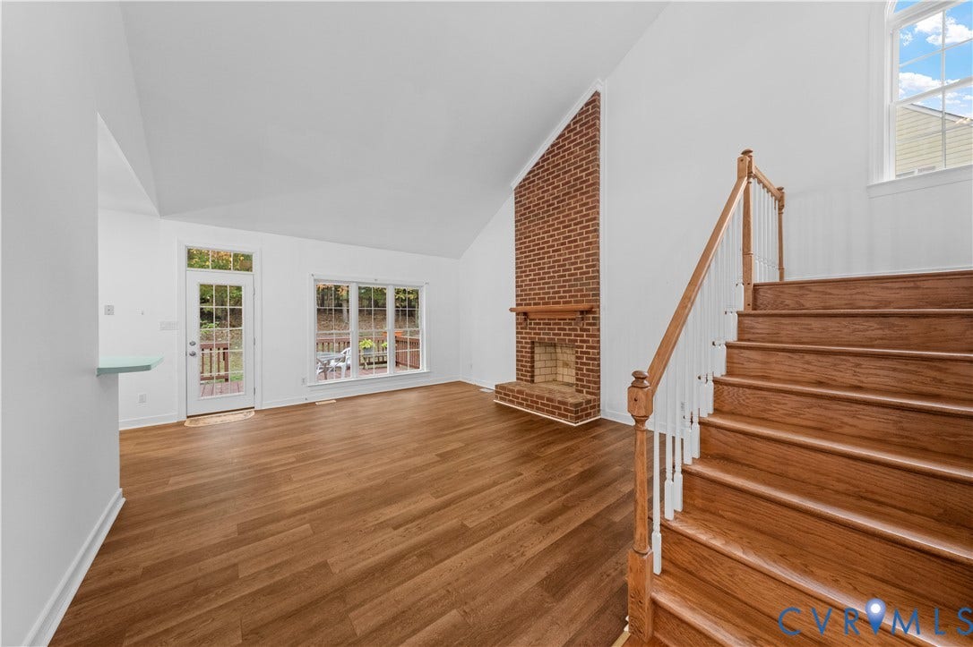 3437 Riverton Court, Robious Road Corridor, Midlothian, VA 23113 Living area featuring a vaulted ceiling, floor-to-ceiling brick fireplace with wood mantel, wood-finish flooring, and a staircase with a wood handrail