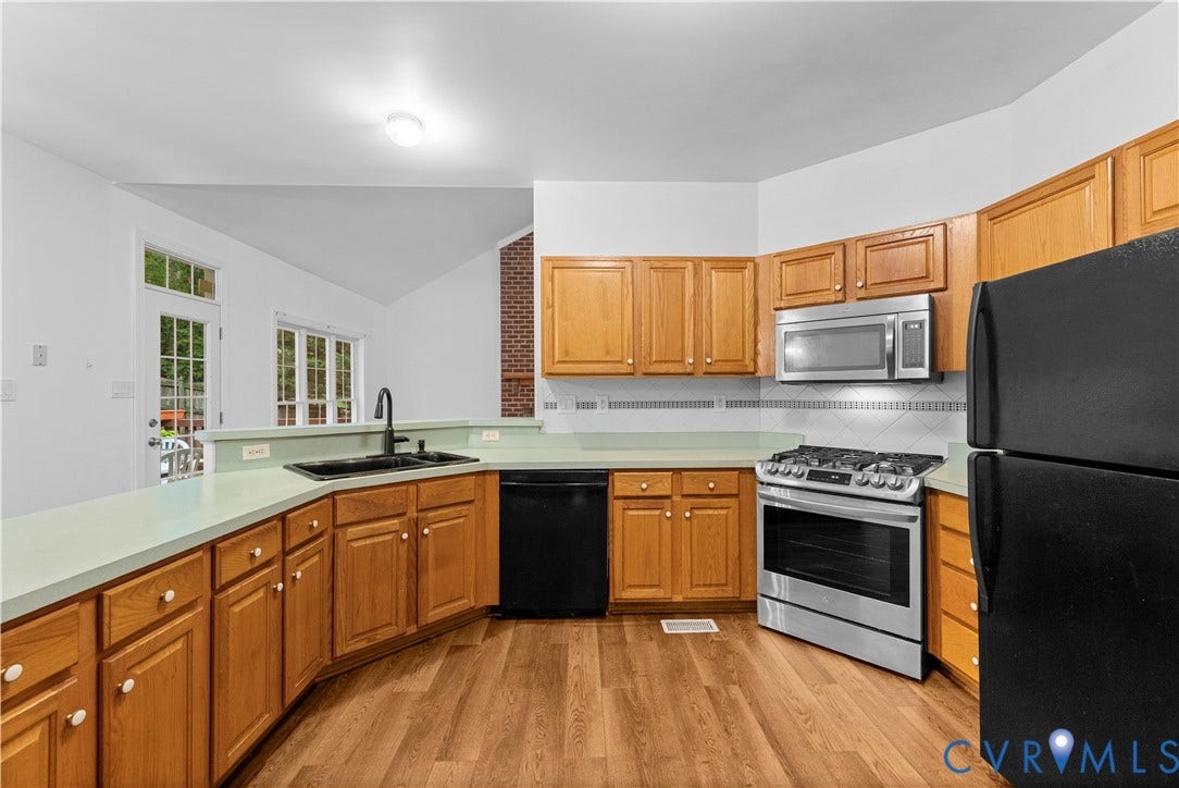 3437 Riverton Court, Robious Road Corridor, Midlothian, VA 23113 Kitchen featuring wood-finish cabinetry, a stainless steel gas range and microwave, a peninsula with a matte black faucet, and a brick accent wall