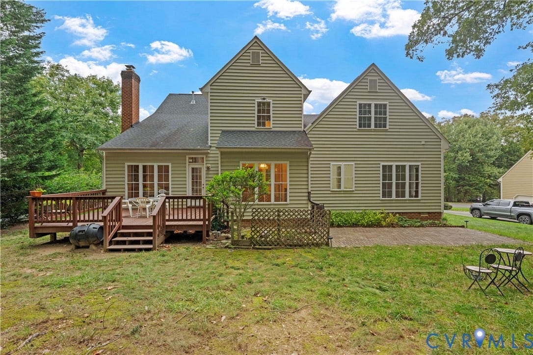 3437 Riverton Court, Robious Road Corridor, Midlothian, VA 23113 Two-story residence with light-colored horizontal siding, a multi-gabled roofline, a raised wooden deck, a paved stone patio, and an external brick chimney