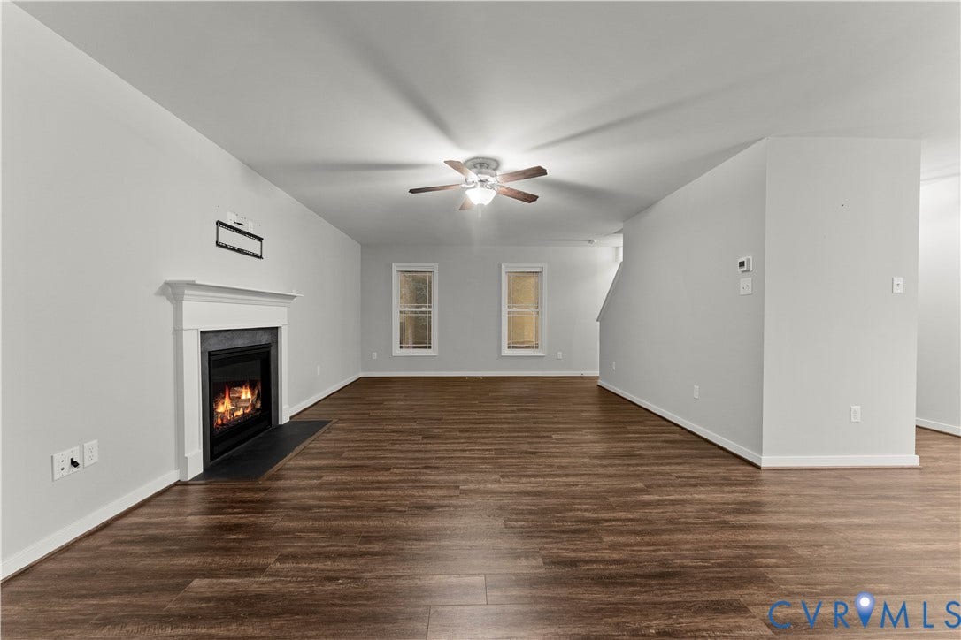 2953 Preston Park Court, Western Goochland County, Goochland, VA 23153 Spacious room featuring wood-finish flooring, a white mantel fireplace with a dark hearth, two windows providing natural light, and a ceiling fan