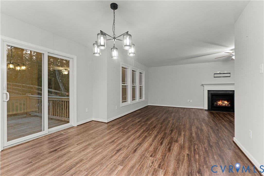 2953 Preston Park Court, Western Goochland County, Goochland, VA 23153 Wood-finish flooring throughout, sliding glass door leading to an outdoor deck, multiple windows with white trim, a black fireplace with a white mantel, and a ceiling fan
