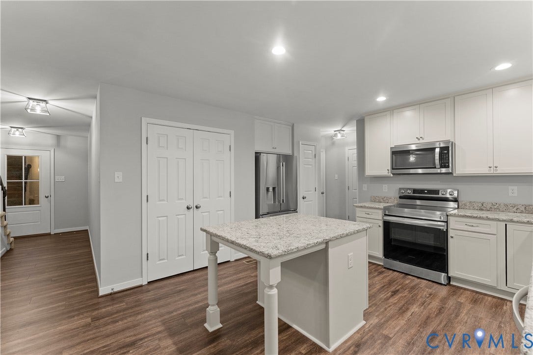 2953 Preston Park Court, Western Goochland County, Goochland, VA 23153 Kitchen featuring an island with a light-toned countertop, white cabinetry, stainless steel appliances, and wood-finish flooring