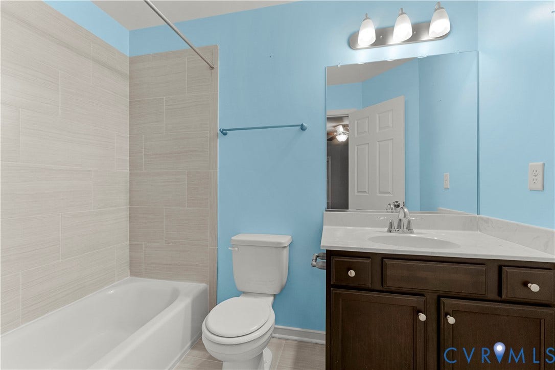 2953 Preston Park Court, Western Goochland County, Goochland, VA 23153 Bathtub with large format tile surround, vanity with dark wood-finish cabinetry, white countertop, and integrated sink