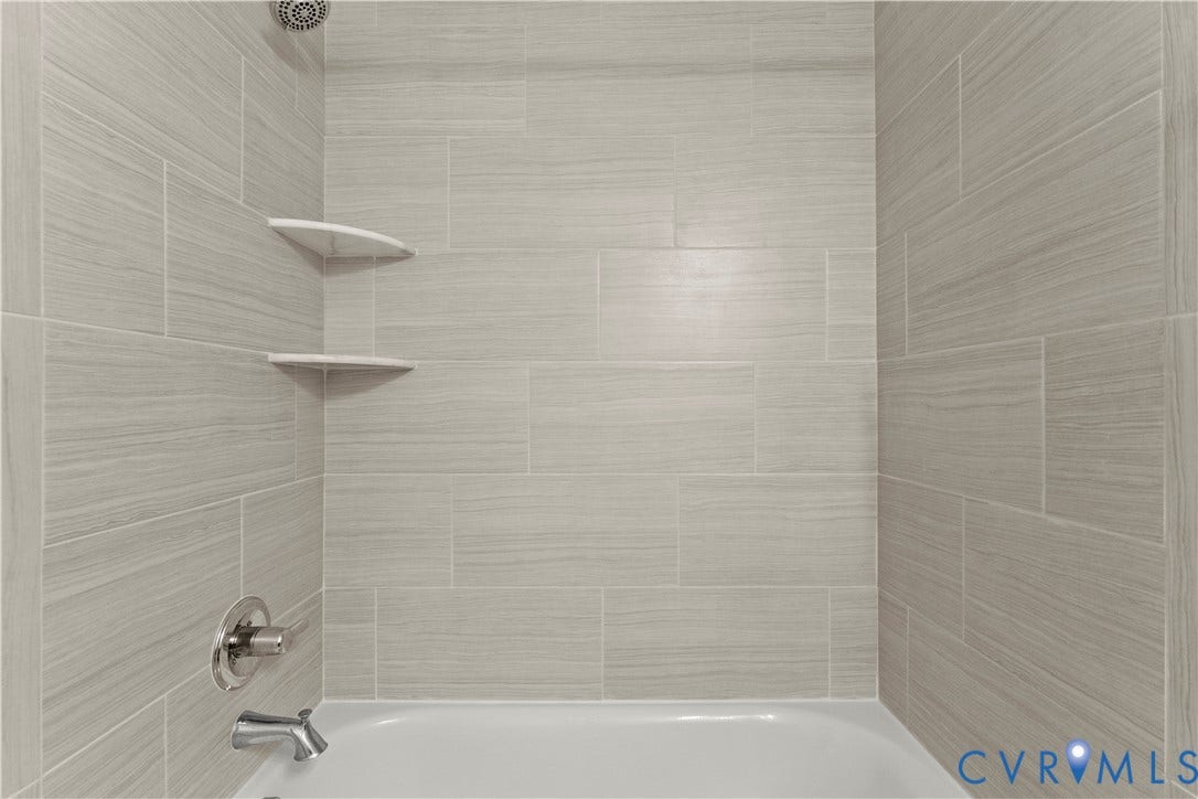2953 Preston Park Court, Western Goochland County, Goochland, VA 23153 Bathtub with light gray textured tile surround, chrome showerhead, and two built-in corner shelves