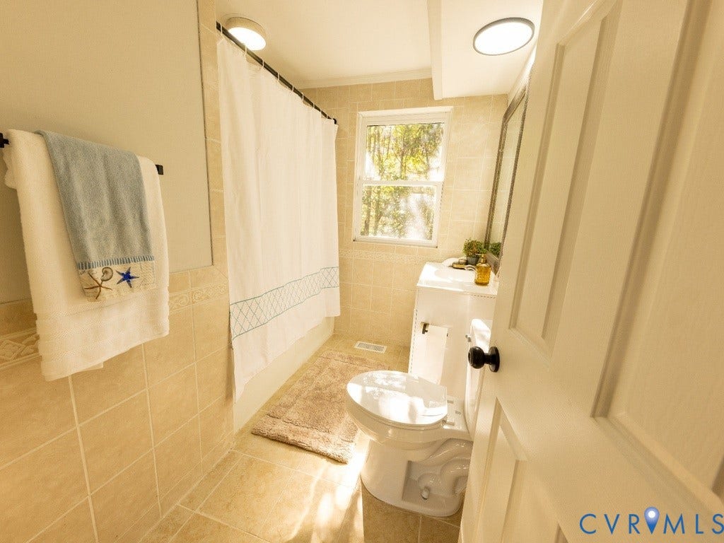 2201 Richmond Street, Hopewell, VA 23860 Tile flooring, tiled shower surround, built-in vanity with sink, window, and flush-mount lighting fixtures