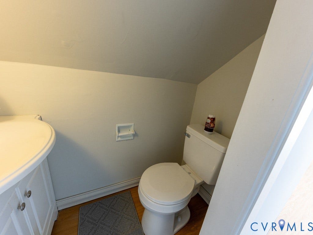 2201 Richmond Street, Hopewell, VA 23860 White built-in vanity with cabinetry and brushed nickel hardware, white toilet, and wood-finish flooring