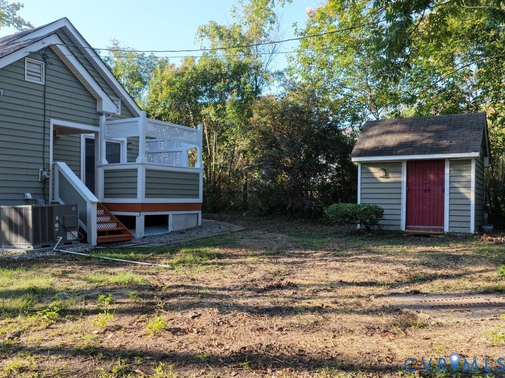2201 Richmond Street, Hopewell, VA 23860 Exterior siding, elevated deck with lattice railing, exterior staircase with wood-finish treads, compact utility shed with a red door, and surrounding mature trees