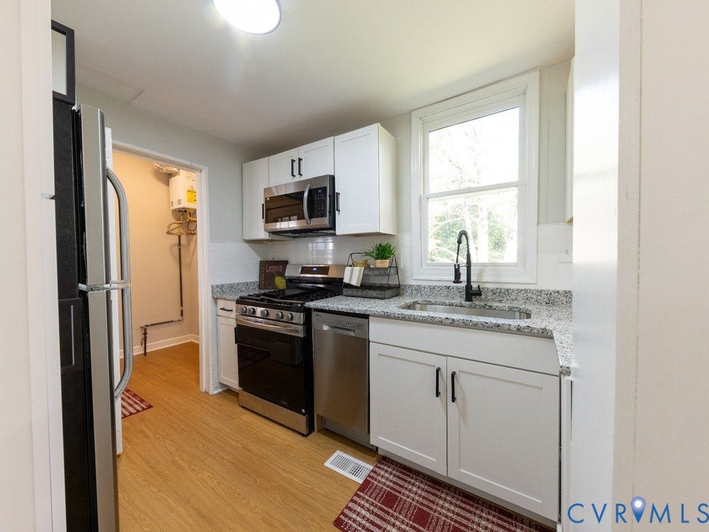 2201 Richmond Street, Hopewell, VA 23860 Kitchen featuring wood-finish flooring, white cabinetry, a black range, stainless steel appliances, and a window with a black faucet