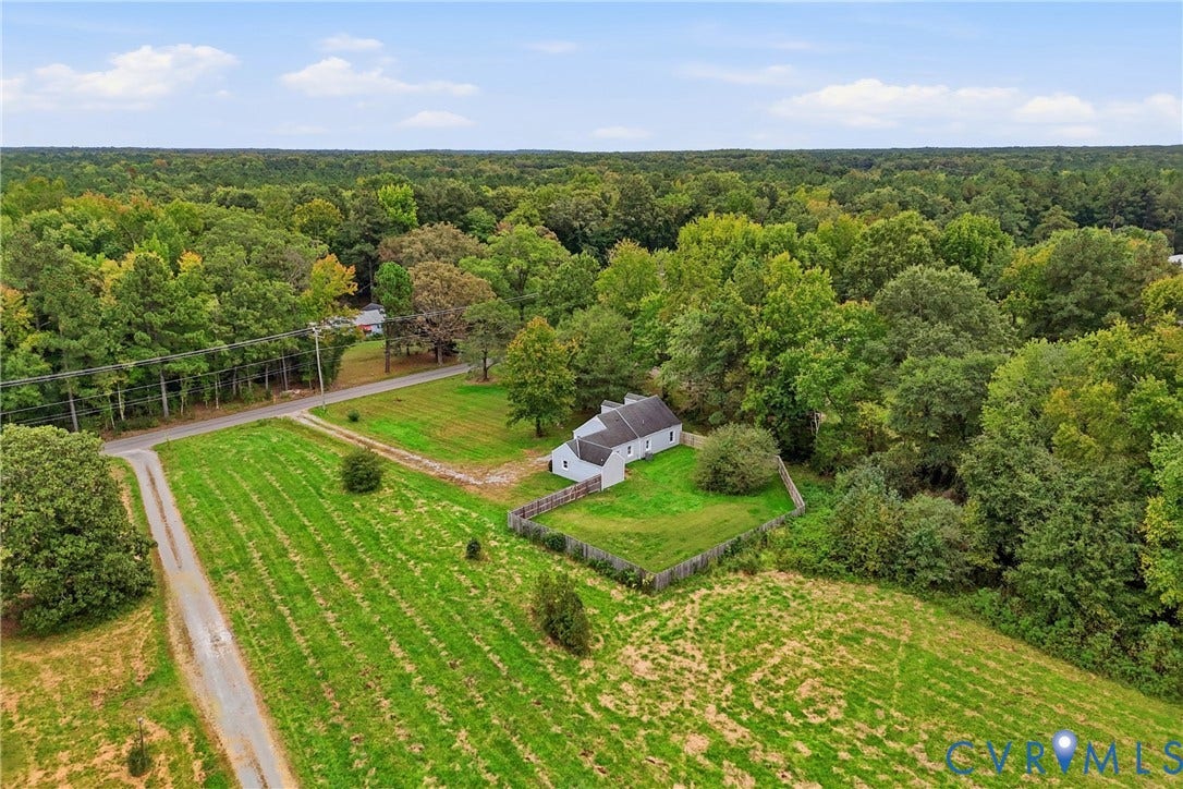 6624 Miller Road, Henrico, VA 23231 Rural property featuring a single-story residence, surrounding wooded areas, and an expansive grassy field